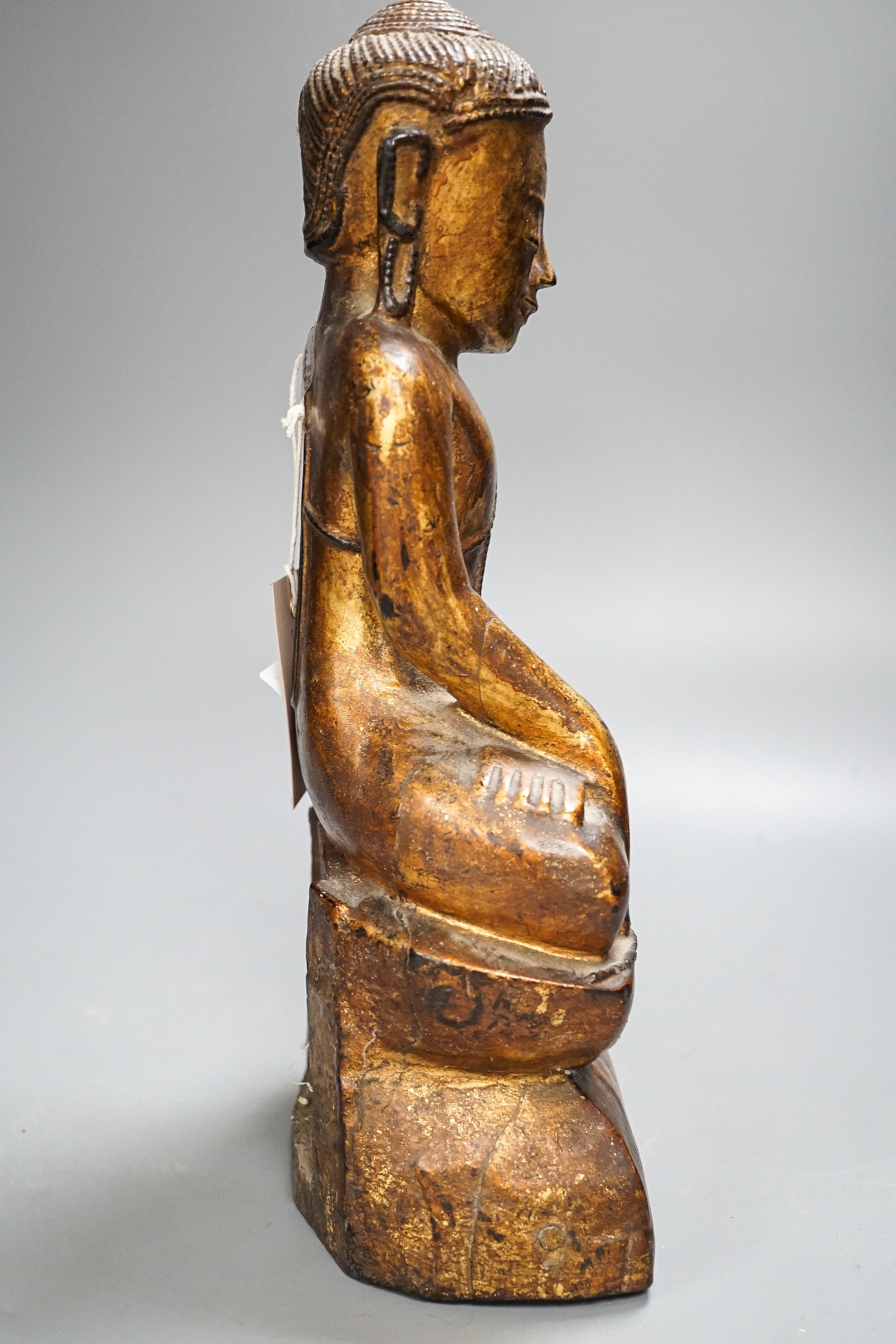 A Burmese gilded carved wooden figure of Buddha, 35 cms high.